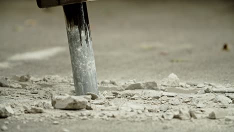 close-up of excavator hydraulic arm rock breaker working on concrete road with sound