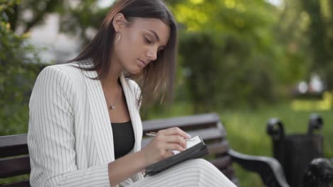 mujer de negocios ocupada escribiendo ideas en un bloc de notas en un banco