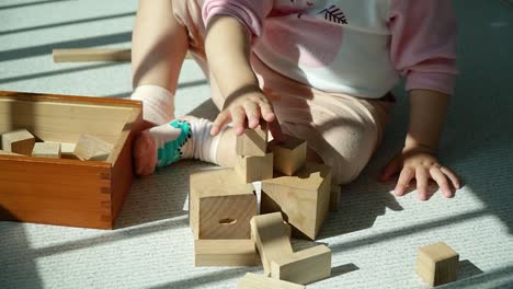 hands of toddler learning by stacking and balancing wooden blocks - multi-ethnic korean-ukrainian baby girl playing