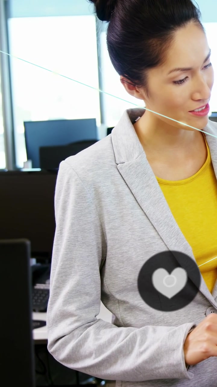 Video verticale: Tecnologa che si china a digitare dati con un'icona a forma di cuore che si espande in una rete.
