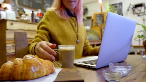 Young-woman-talking-on-the-phone-while-using-laptop-in-cafe-4k