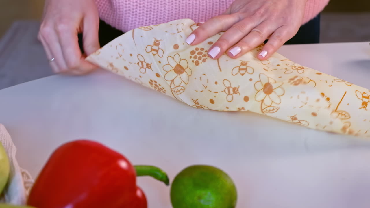 Woman hands wrapping a fresh yellow pepper in beeswax food wrap