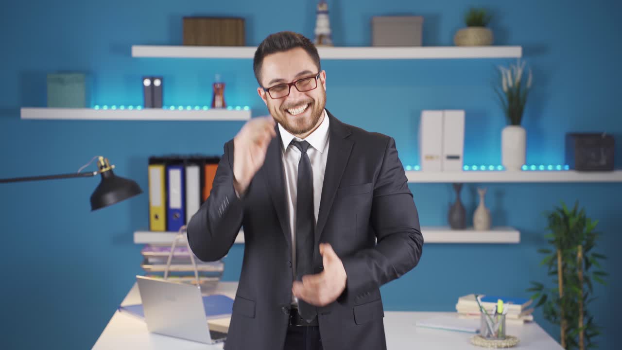 un hombre de negocios feliz aplaudiendo mirando a la cámara.