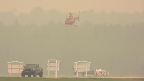 an emergency helicopter takes off in a dense smoke of a forest fire