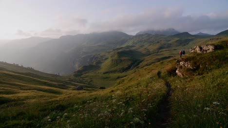 Mountain-landscape-shot-with-hikers-on-trail-on-the-right-and-sun-very-low-shining-from-the-left