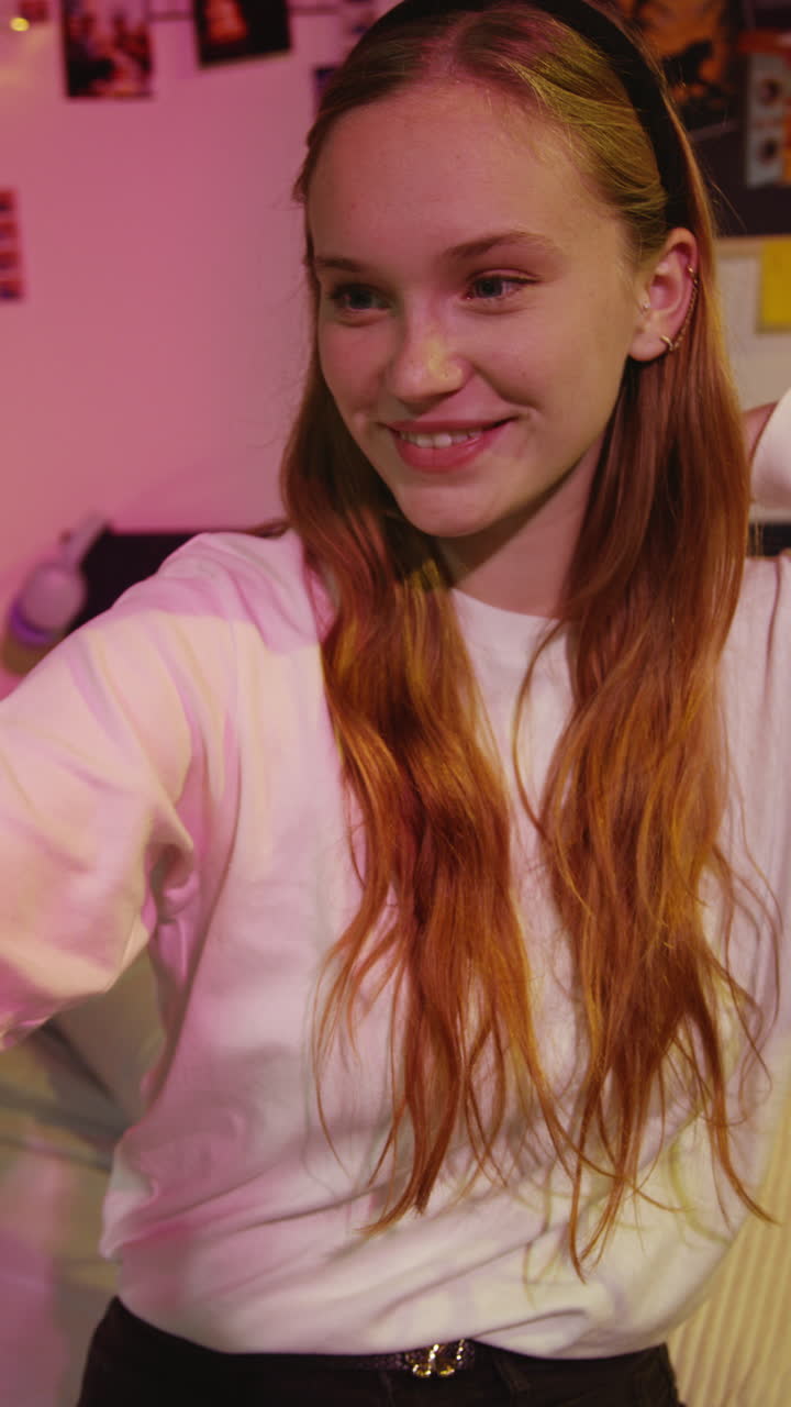Young woman smiling and looking at her phone in a bedroom