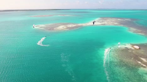 two men kitesurfing near house typical of primitive civilizations built on wooden stakes, inside caribbean sea