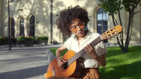 african-american woman artist playing guitar and singing, street performance