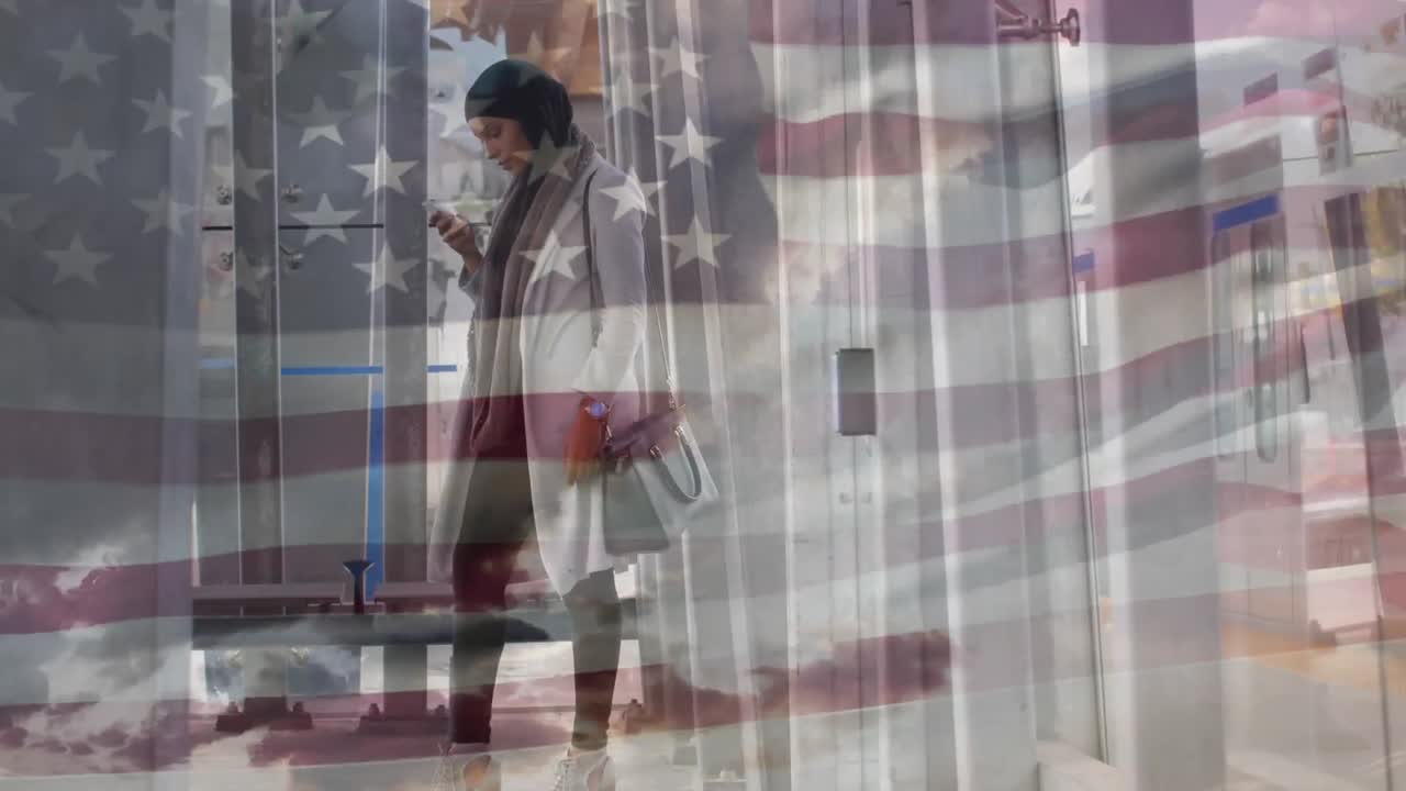 animación de la bandera estadounidense ondeando sobre una mujer de raza mixta en hijab usando un teléfono inteligente