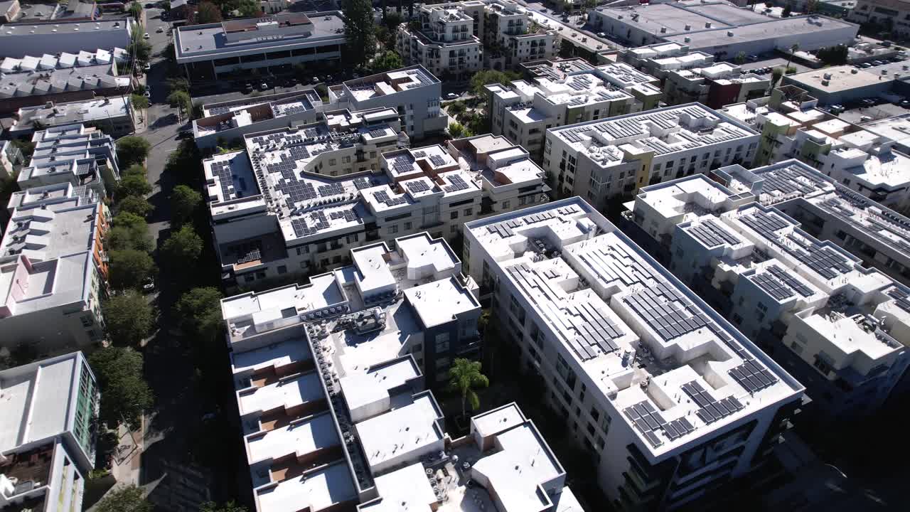 volando sobre un gran complejo de apartamentos de pasadena con vista aérea de los tejados de paneles solares