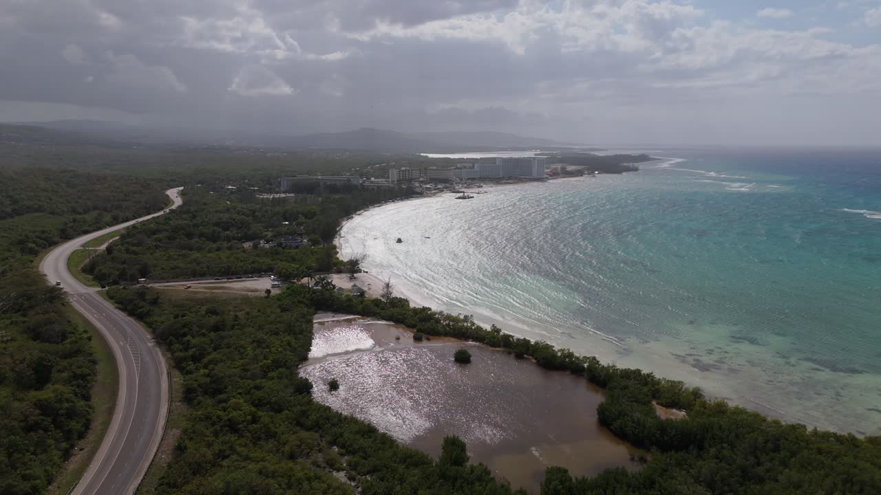 Wide Aerial view of a beach in Falmouth, Jamaica, showcasing turquoise waters, white sand, and lush coastal scenery