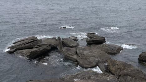 View-across-rocky-coastal-shoreline-with-tide-in-slow-motion-waters-crashing-about-rocks