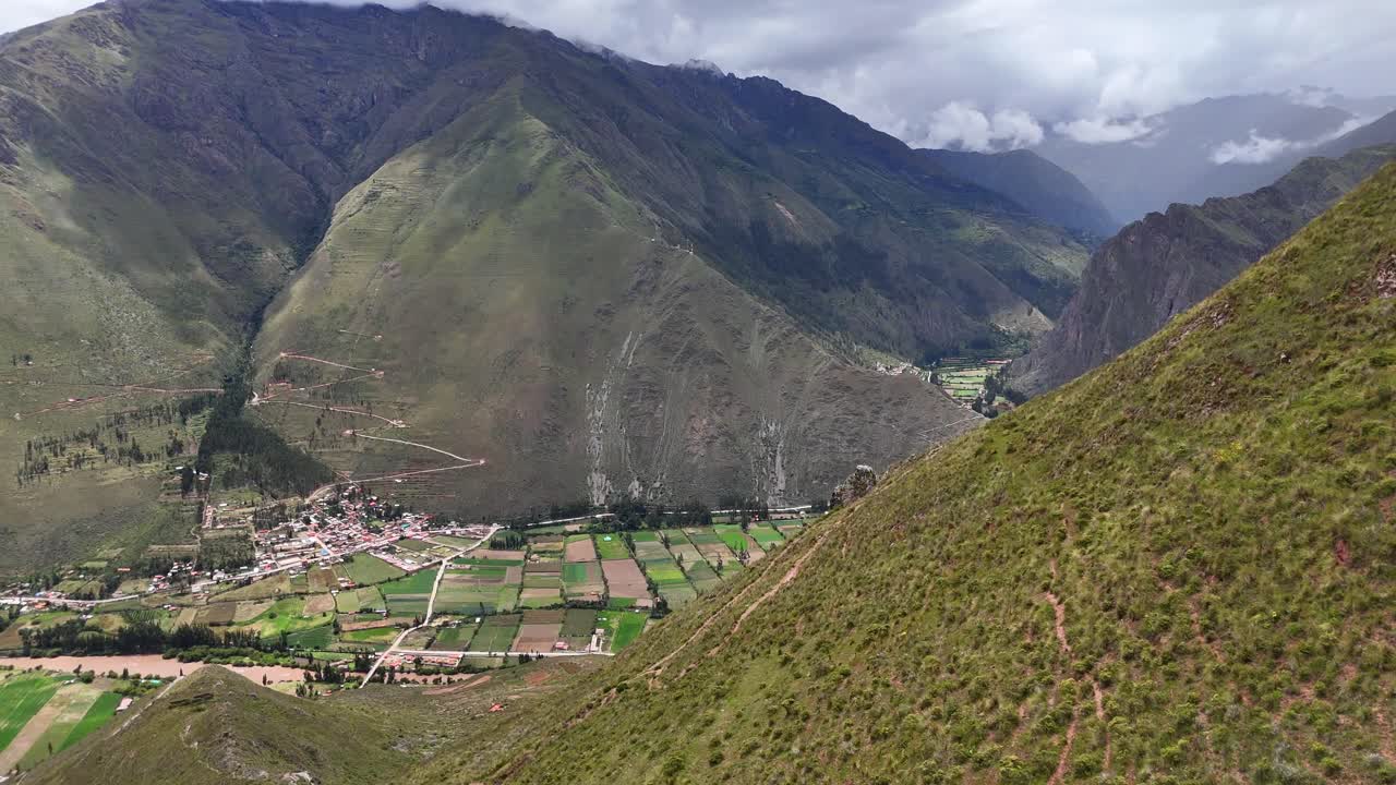 Aerial Drone view of wild horses running along a grassy mountain range in Ollantaytambo Peru