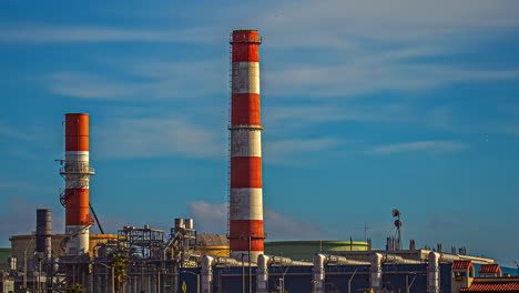 Lapso-De-Tiempo,-Nubes-Moviéndose-Sobre-Chimeneas-Y-Silos-De-Refinería-De-Petróleo