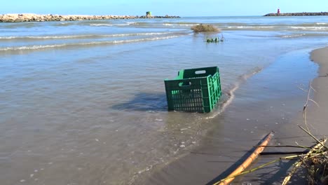 a plastic crate in the water on a beach, illustrating the seriousness of plastic pollution in our oceans