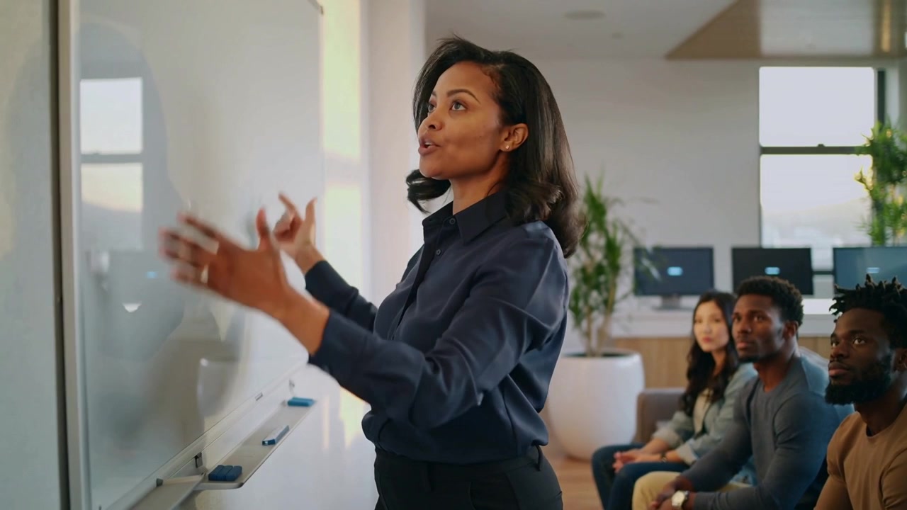 Standing up woman in navy top gesturing, explaining concepts in office with whiteboard, copy space