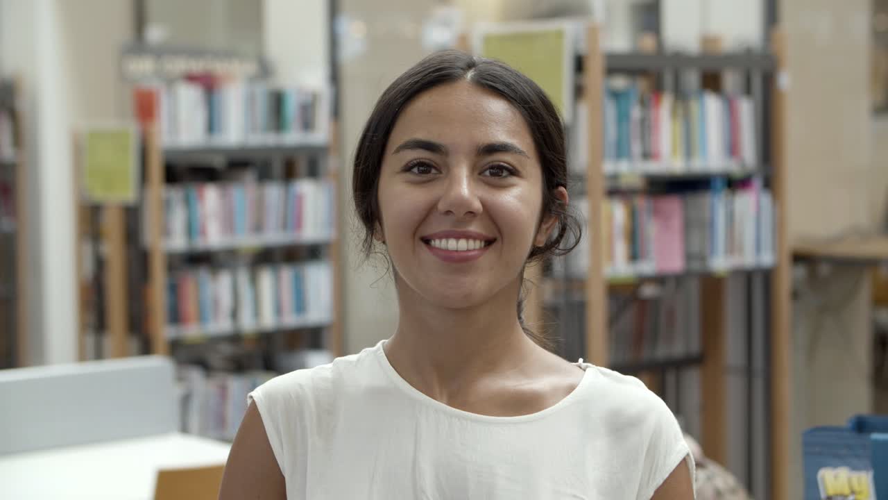 bella mujer asiática con blusa blanca parada en la biblioteca