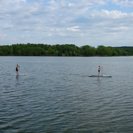 young people doing water sport in the evening. active friends swimming along a river standing on a boat with oars. healthy lifestyle. view from above