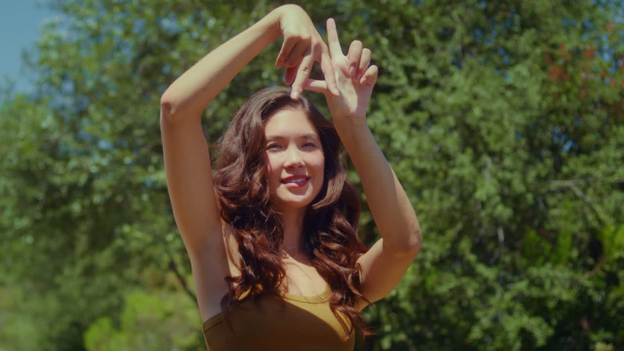 공원에서 손가락으로 라 사인을 보여주는 여성. 아시아 소녀가 제스처를 하는 도시 이름