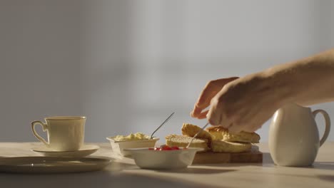 fotografía de estudio de una persona con el tradicional té de la tarde británico con crema de bollos y mermelada 3