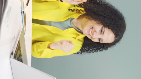 Vertical-video-of-Young-woman-looking-at-laptop-applauding.