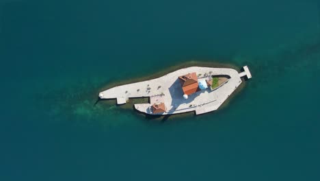 Vista-Aérea-De-Arriba-Hacia-Abajo-Del-Islote-De-Nuestra-Señora-De-Las-Rocas-Frente-A-La-Costa-De-Perast-En-La-Bahía-De-Kotor,-Montenegro