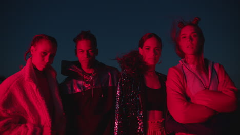 group of friends posing in city at night wearing stylish urban fashion looking confident young people enjoying nightlife with red light