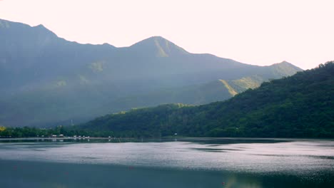 rays of sunlight breaking over mountains and lighting up a cool and calm lake in early morning