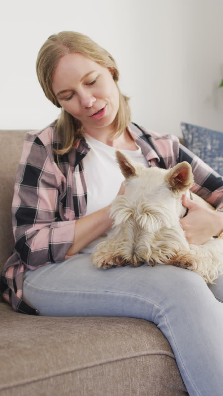 Verticale video van blije Kaukasische vrouw die haar hond thuis aait