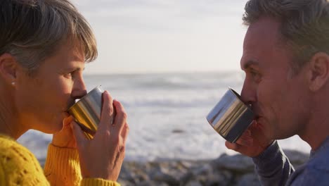 una pareja bebiendo café junto al mar.