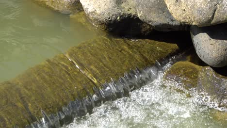 a small waterfall flowing into a small vir, a lot of beautiful water splashes