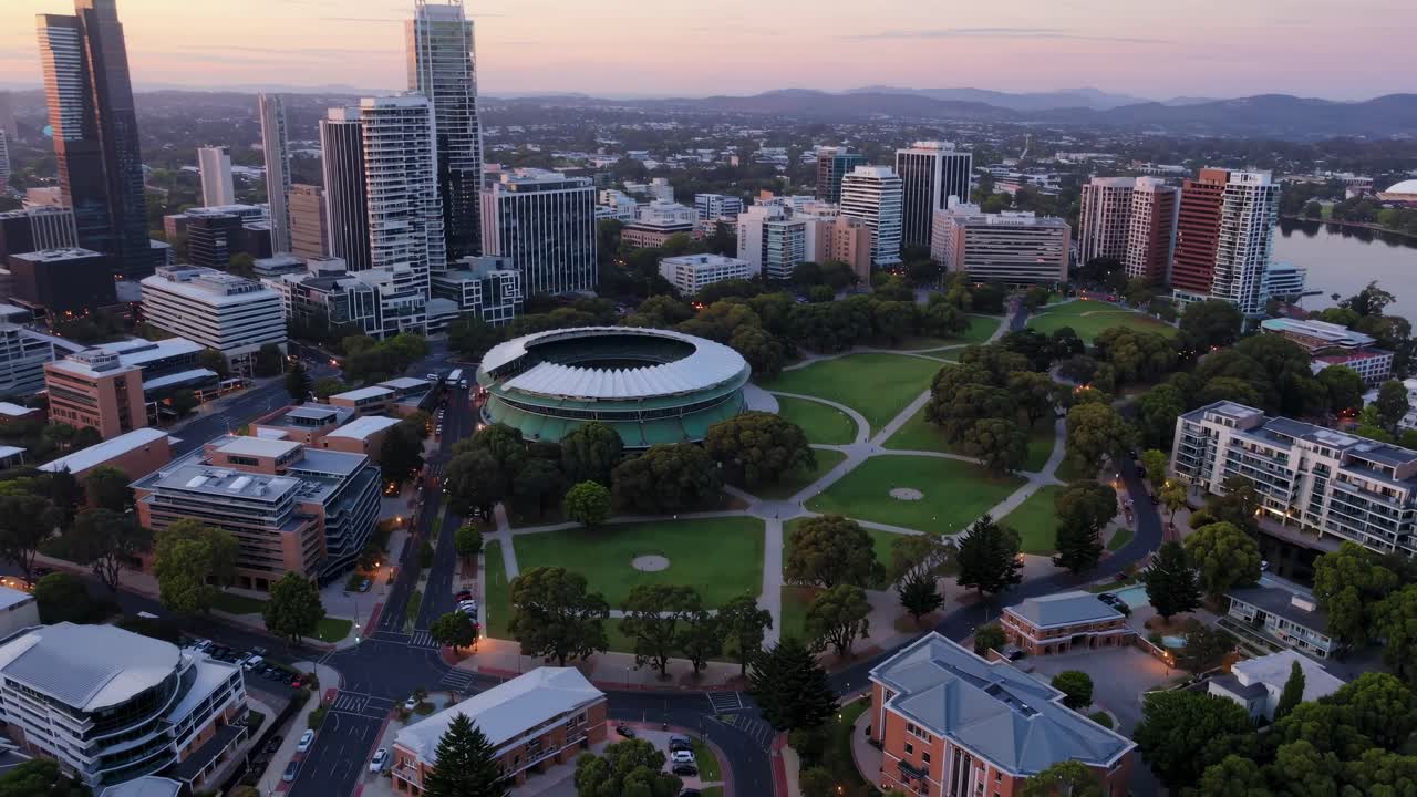Aerial view of a cityscape at sunset, showcasing modern skyscrapers and green spaces