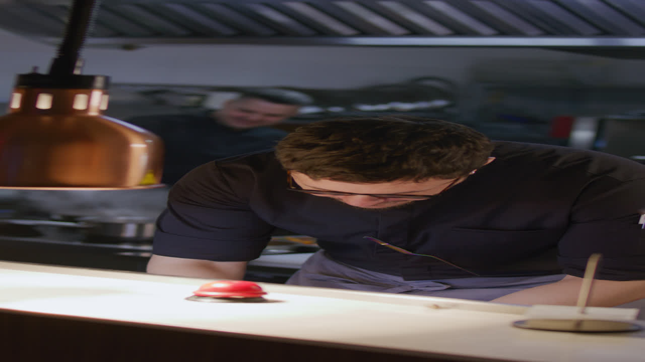 Chef che legge la comanda e coordina il flusso di lavoro nella cucina del ristorante.