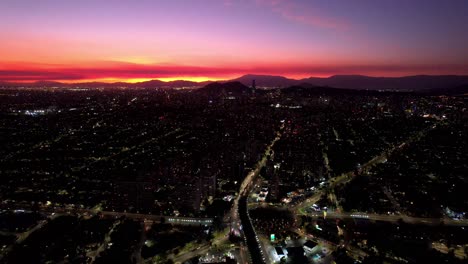 Puesta-De-Sol-De-Santiago-De-Chile,-Rotonda-De-Atenas,-Tráfico-Urbano-Cielo-Aéreo-Carreteras-De-La-Ciudad-Horizonte-Degradado-Dorado-Y-Amarillo-Sobre-La-Cordillera-Andina