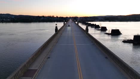 aerial view of vehicles driving on suspension bridge between columbia and wrightsville borough during sunset time - wide shot