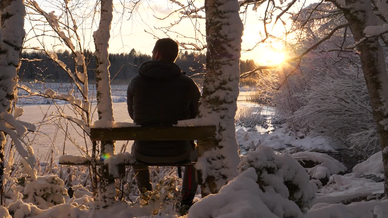 Hiking man watching sunset in winter landscape