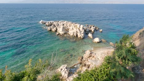 view looking down at tree overlooking rocky shoreline with turquoise waters at kassiopi