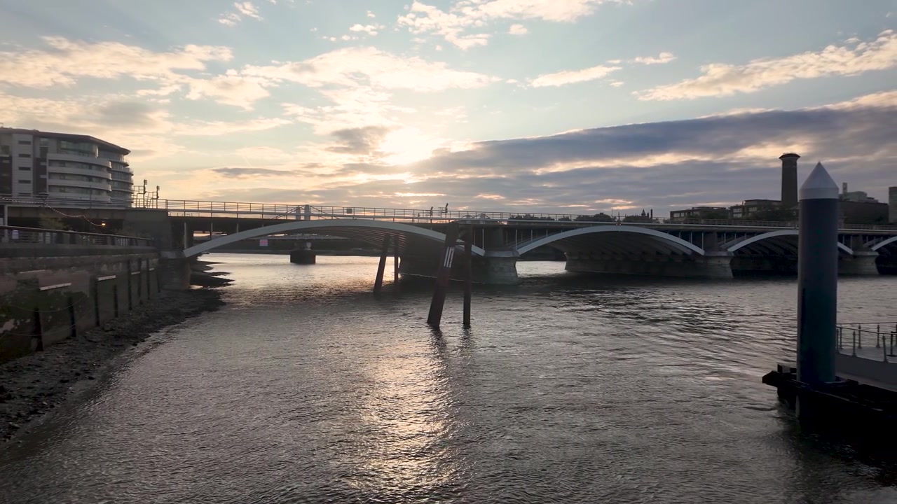 Vakkert solnedgangslys reflekteres på Themsen i London med Grosvenor Bridge i sikte. Panorerende opptak
