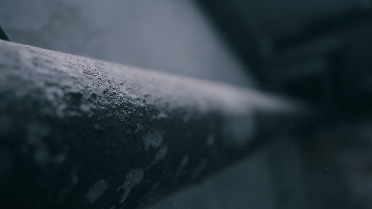 Tubazioni su una superficie muraria strutturata in penombra con tonalità blu. Scena industriale inquietante adatta a temi di crimine, pericolo o thriller
