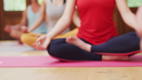 Low-section-of-diverse-group-sitting-in-yoga-lotus-position-during-yoga-class-at-studio