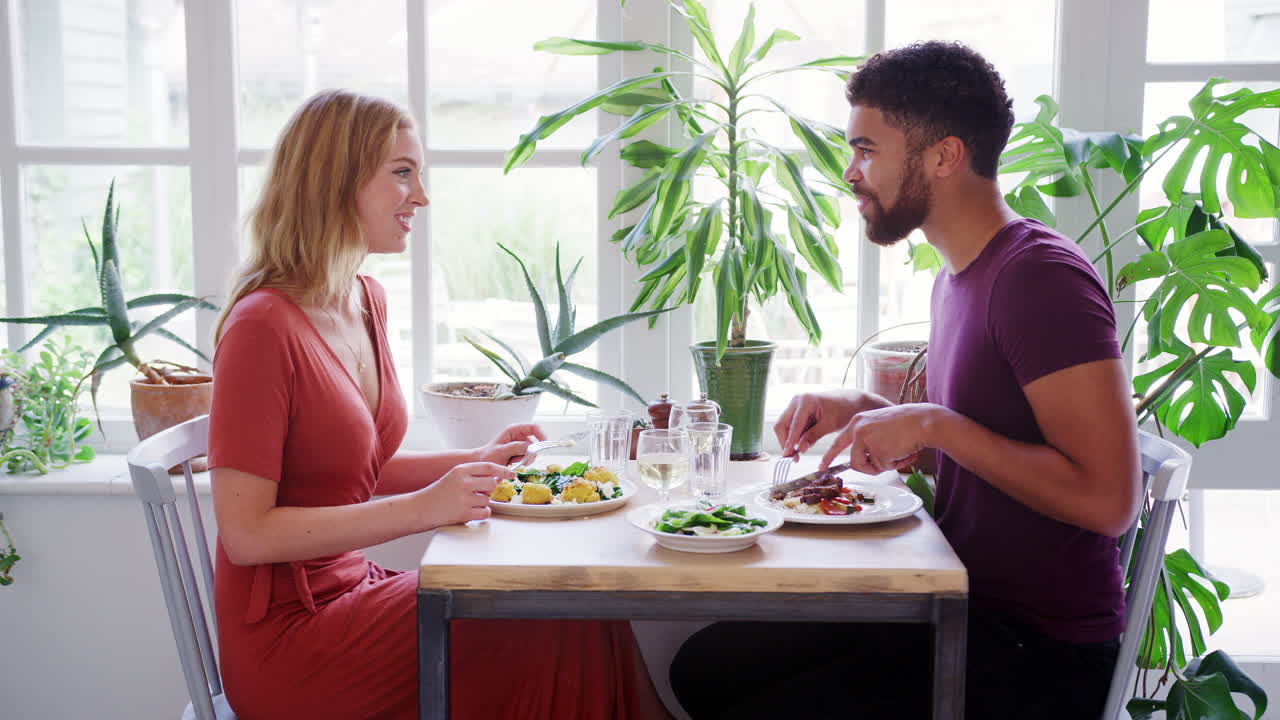 Mixed race couple eating dinner together at a restaurant, side view, close up
