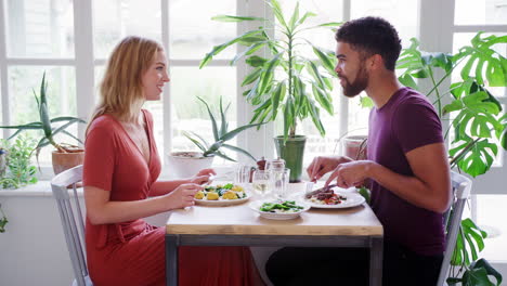 Mixed-race-couple-eating-dinner-together-at-a-restaurant,-side-view,-close-up