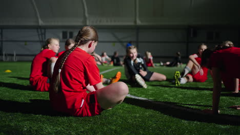 young girls soccer team stretching on indoor field