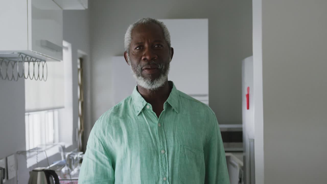 アフリカ系アメリカ人の高齢男性がカメラに向かって微笑み ⁇ 社会的距離で飲み物を飲んでいます ⁇