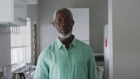 A-senior-African-american-man-smiling-at-the-camera-and-drinking-a-beverage-in-social-distancing