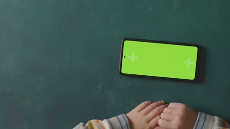 overhead shot of child holding green screen digital tablet horizontally watching or streaming content 3