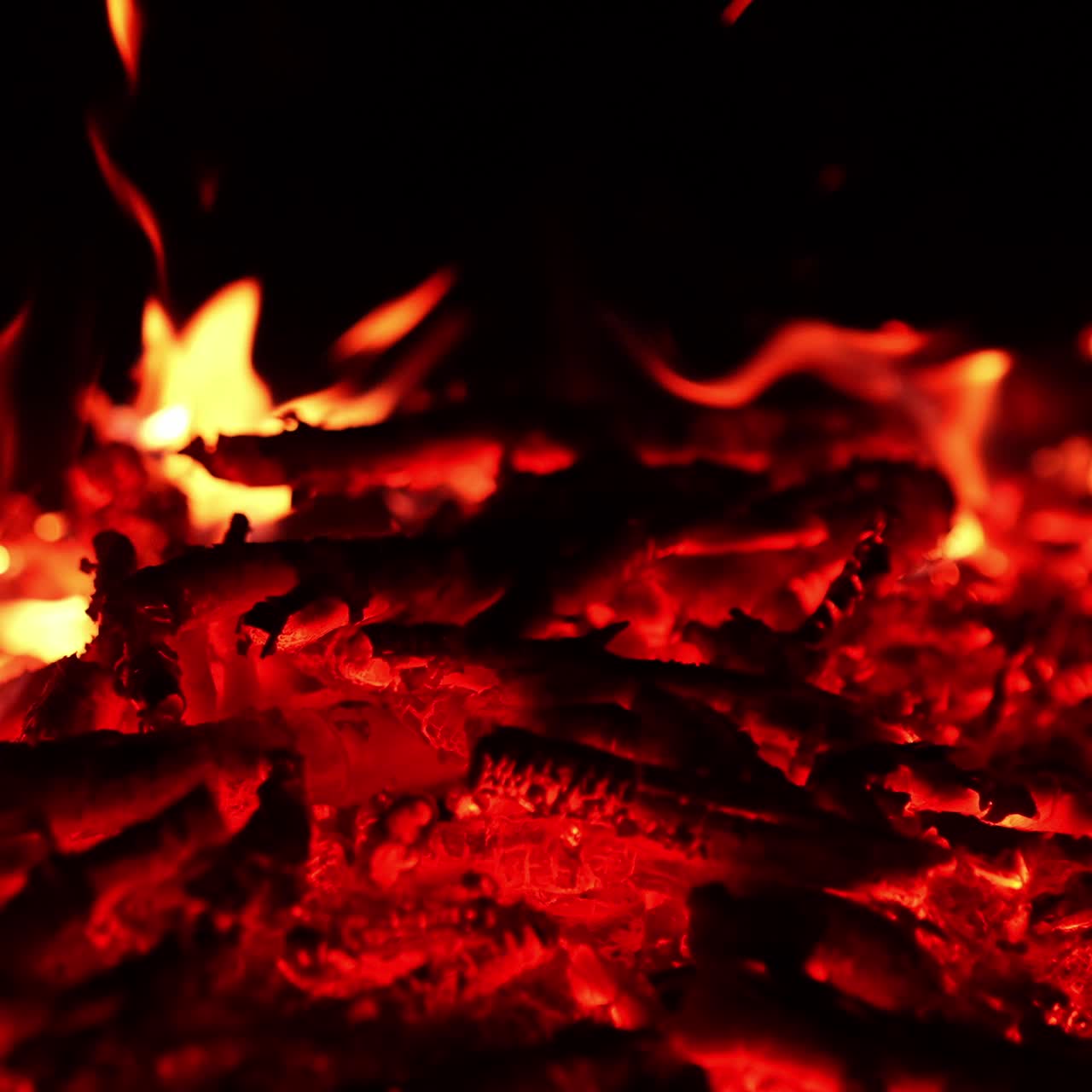 Amazing red hot embers left from the campfire. Little flames are burning at backdrop