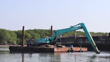 excavator moves, lifts objects on a river barge