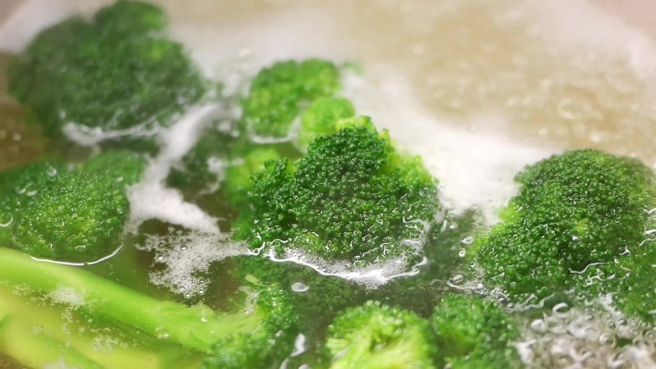 Cimette di broccoli freschi che bollono in una pentola d'acqua