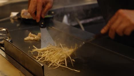 chef expertly prepares noodles on a hot grill.